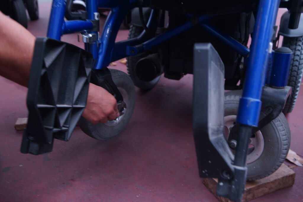 義工清潔輪椅輪胎積藏的泥塵。