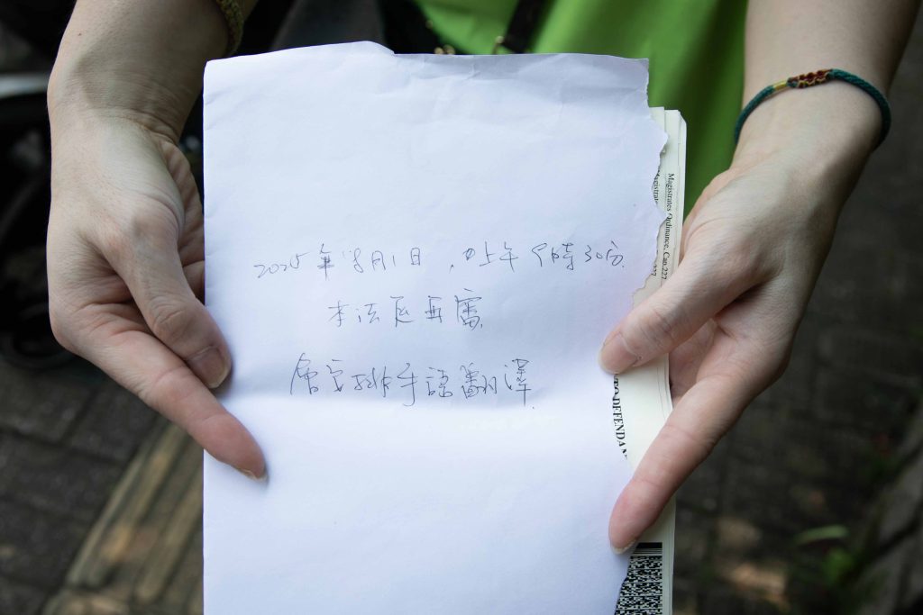 郭小姐走到被告席上表明需要手語譯者協助，控方律師用筆紙承諾8月1日會安排手語傳譯員。